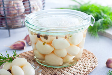 pickled garlic with spices in a glass bowl, horizontal