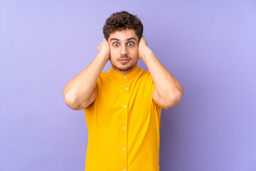 Caucasian man isolated on purple background frustrated and covering ears