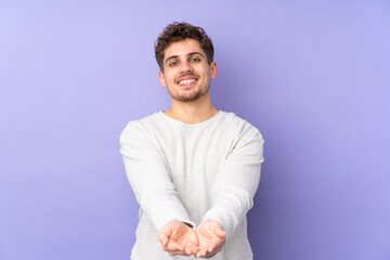 Caucasian man isolated on purple background holding copyspace imaginary on the palm to insert an ad