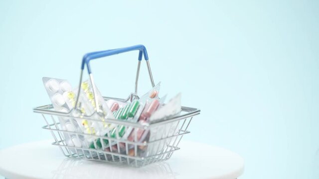 Selective focus of shopping basket with pills on blue background