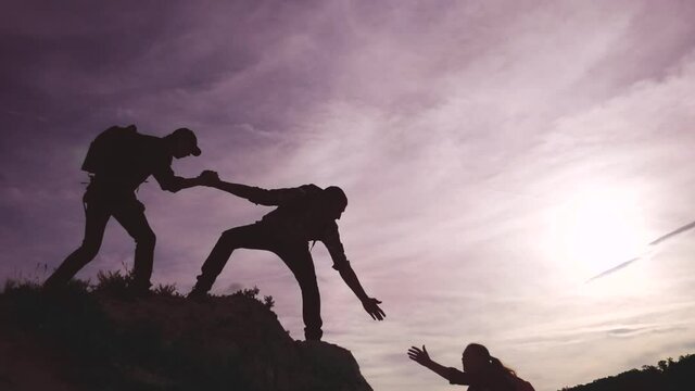teamwork help business travel silhouette concept. group team of tourists lends a lifestyle helping hand climb the cliffs mountains. teamwork people climbers climb to top lifestyle overcoming hardships