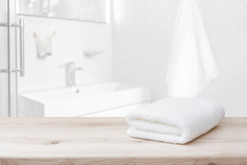 Fototapeta na wymiar White towel with space on wood and blurred bathroom interior