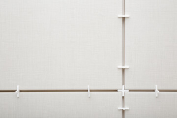 White plastic cross in seam between gray ceramic tiles. Closeup. Empty place for text. Top down view. © fotoduets