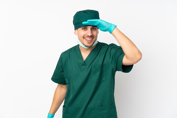 Surgeon in green uniform isolated on isolated white background looking far away with hand to look something