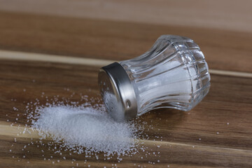 Salz und ein Salzstreuer liegen auf einem Brettchen aus Holz