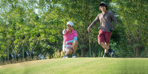 Happy and cheerful of the woman golf player in winning putt a ball completed into the hole on the...