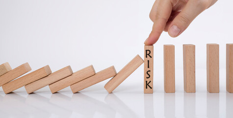 domino effect and risk management concept. manager stops falling wooden cubes with his finger.