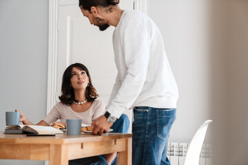 Image of pleased beautiful couple having breakfast while talking