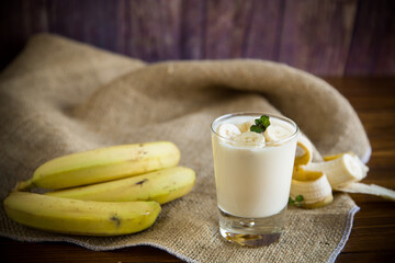 tasty homemade yogurt with bananas in a glass on a wooden table