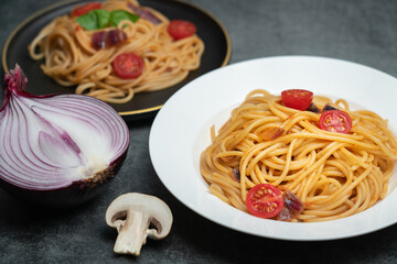 Delicious tomato and mushroom spaghetti on a white plate, spaghetti on a black plate