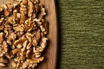 Top view of pistachios on a wooden board on a dark background.
