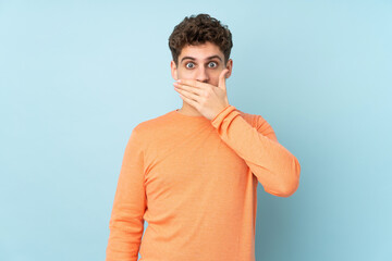 Caucasian man isolated on blue background covering mouth with hands