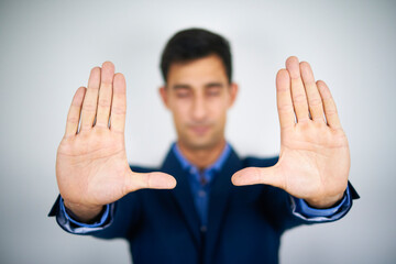 A businessman holding his palms high while closing his eyes. Concentration, focus and meditation concept.