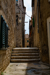 Fototapeta na wymiar Calle pintoresca de piedra con escaleras y bandera de fondo