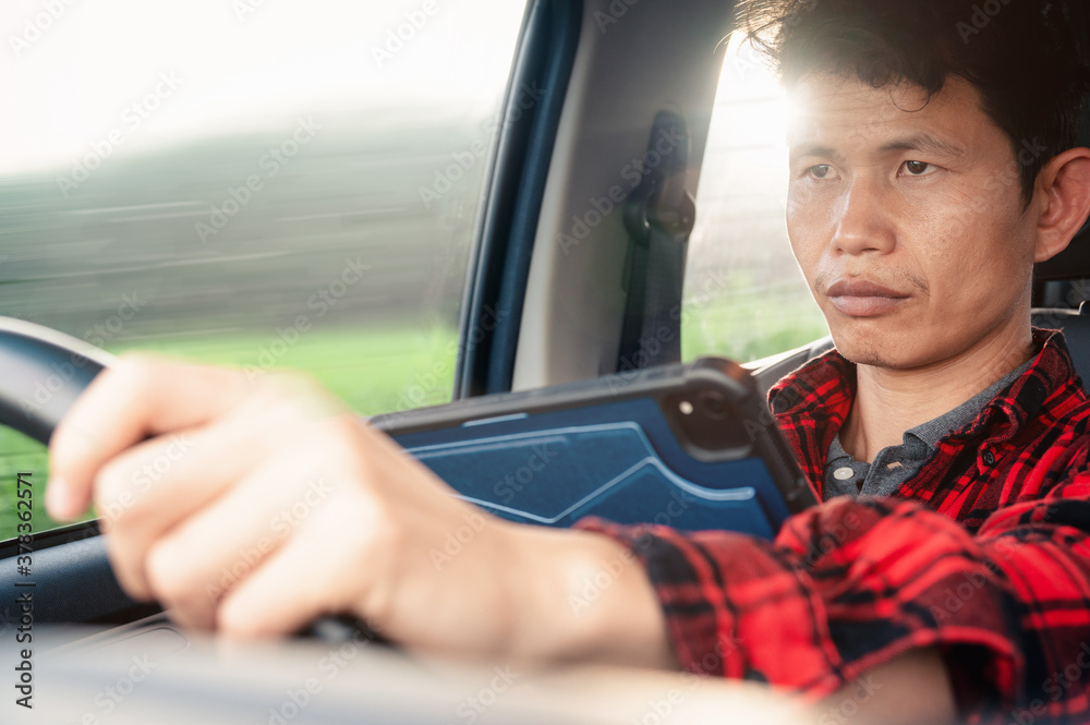 Poster man use tablet or phone while driving a car his looking on a device and road and steering a wheel an