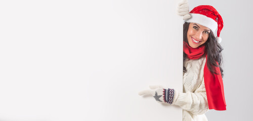 Fototapeta premium Christmas dressed female behind a white board with space for a sign