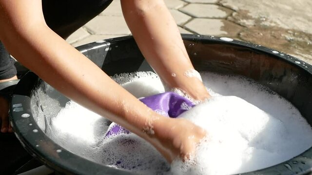 Women washing clothes by hand with detergent in enamelware. Household work and hygiene concepts. 