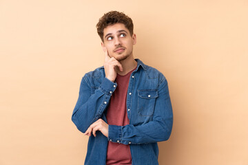 Caucasian man isolated on beige background thinking an idea