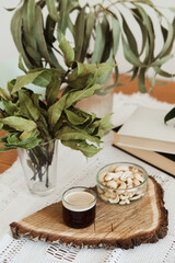 themed coffee corner with dried eucaliptus and bay leaves and retro tablecloth, autumn vibes, upcycled glass botles transformed into the cup and small bowl on the wooden cut with the bark