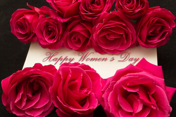 Happy Womans Day March 8th written on white card with red roses