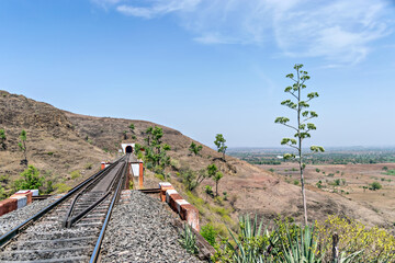 Single line railway track passing over bridge to enter a tunnel.