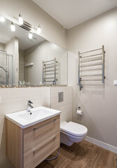 Modern interior of bathroom in luxury apartment. Sink with wooden drawers. WC toilet. Hardwood floor.
