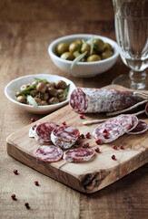  Sliced french salami with fresh rosemary and olives on rustic wooden background