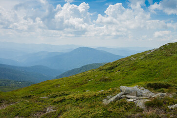 Fototapeta premium Mountain landscape. View of the mountain with green meadows against the background of beautiful clouds