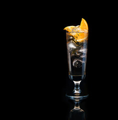Fresh alcoholic cocktail with vodka, ice and slice of orange in glass on black background