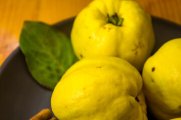 large yellow quince fruits on a ceramic plate, with anise, cinnamon, and walnuts