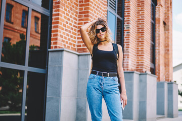 Woman in denim fluffing hair while standing on street