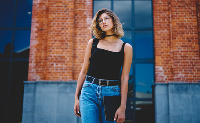 Pensive young lady chilling near modern building