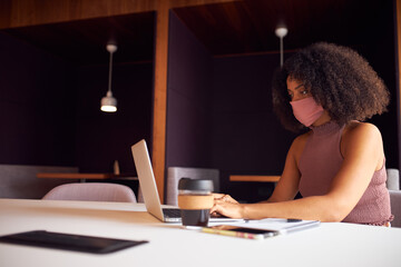 Fototapeta premium Businesswoman Wearing Mask Working At Laptop In Office During Health Pandemic