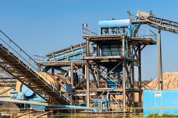Fototapeta na wymiar Cement mill sand dewatering machine and machine for transferring gravel, spoil for transport belts on blue sky at an industrial cement plant.