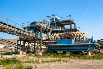 Cement mill sand dewatering machine and machine for transferring gravel, spoil for transport belts on blue sky at an industrial cement plant.