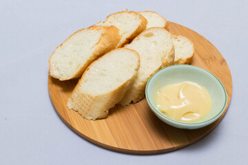 Butter on wooden holder surrounded by bread and milk on natural background