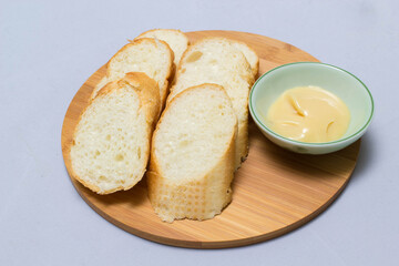 Butter on wooden holder surrounded by bread and milk on natural background