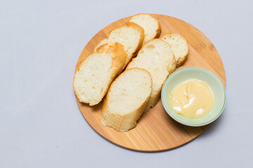 Butter on wooden holder surrounded by bread and milk on natural background