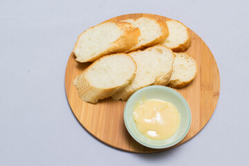 Butter on wooden holder surrounded by bread and milk on natural background