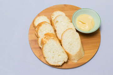Butter on wooden holder surrounded by bread and milk on natural background