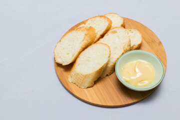 Butter on wooden holder surrounded by bread and milk on natural background