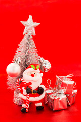 Santa and snow christmas tree with silver present on red background.