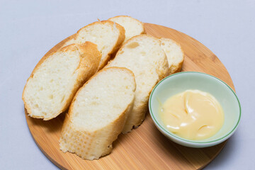 Butter on wooden holder surrounded by bread and milk on natural background