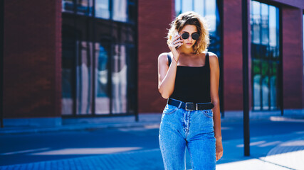 Thoughtful young female talking on cellphone outside