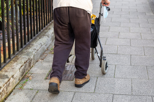 An Elderly Man Walking Using A Walking Aid Or A Zimmer Frame