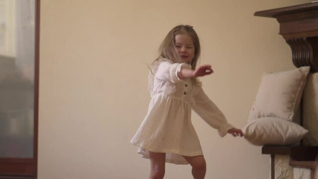 Cheerful children's dance. Little girl is dancing in a white dress. The child is at the party. High quality FullHD footage
