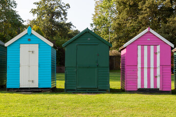 Fototapeta na wymiar Three colourful wooden beach huts at the british seaside