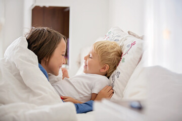 Obraz premium Two sweet children, boy brothers, lying in bed together, talking