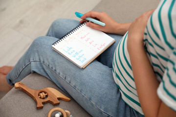 Pregnant woman with baby names list sitting on sofa, closeup