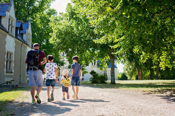 Father with three children, walking together in park in front of castle